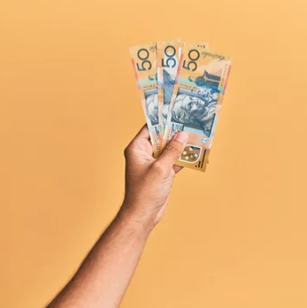 hand holding Australian 50 dollar notes, orange background